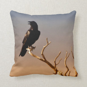 Coussin Raven sur les branches d'arbre ensoleillées,