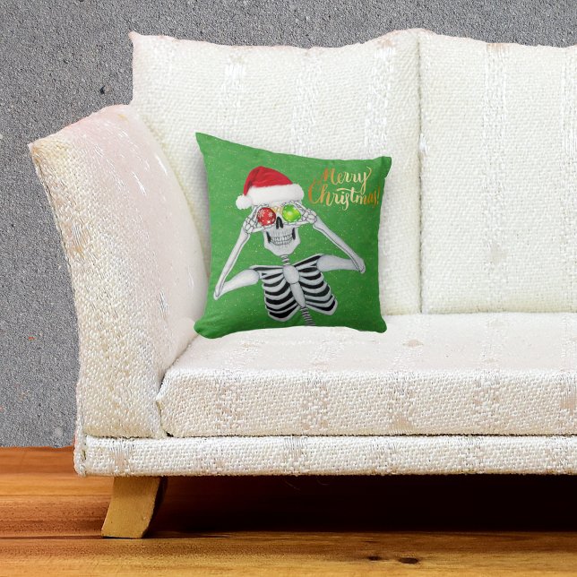 Coussin Squelette souriant tenant des ornements aux yeux v (Happy Merry Christmas Skeleton in Santa hat with ornaments on green throw pillow.)