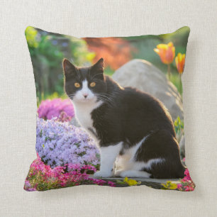 Coussin Un joli chat noir blanc dans un jardin fleuri colo