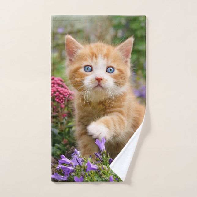 Cute chaton gingembre dans un jardin jouant avec u (Serviette à main)