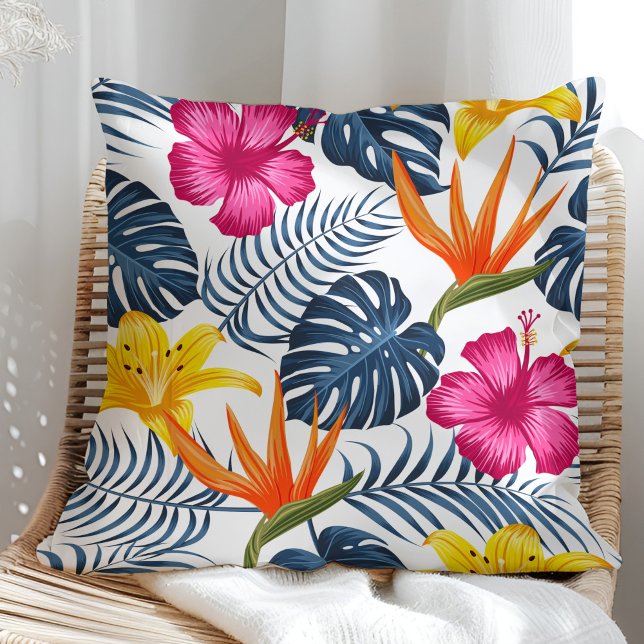 Design tropical coloré sur un coussin blanc (Colorful tropical design on a white pillow in a sunny rattan armchair.)