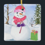 En Céramique Snowman avec foulard rose et ornement sucre de can<br><div class="desc">Snowman avec une écharpe rose et portant un sucre de canne. Paysage d'hiver et sac cadeau en vert citron avec un ours et la sucette à côté du bonhomme de neige. À l'arrière,  votre nom,  l'année et les jours de neige heureux peuvent être personnalisés. Aquarelle.</div>