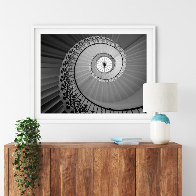 Escalier en spirale avec affiche de fleurs (Spiral Staircase with Flowers Poster in a white frame above a small furniture.)