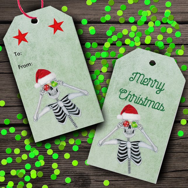 Étiquettes-cadeau Drôle Squelette OEuvres d'ornement Rouge Étoiles V (Silly Skeleton ornament eyes Santa Hat red stars on green hanging Christmas gift tags.)