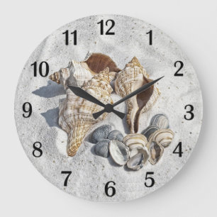 Grande Horloge Ronde Une collection de coquillages sur du sable avec de