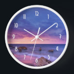 Horloge Belle photo côtière du coucher de soleil<br><div class="desc">Une horloge avec une belle photo aux couleurs saisissantes de violet,  bleu et rose au coucher du soleil. Un joli littoral parsemé de rochers.</div>