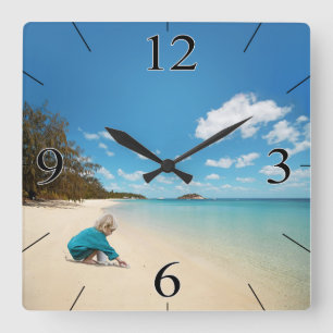 Horloge Carrée Petite fille sur la plage avec coquillages