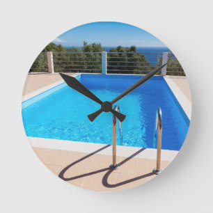 Horloge Ronde Blue swimming pool with steps at sea