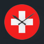 Horloge Ronde drapeau suisse<br><div class="desc">Le drapeau de la Suisse (allemand : Schweizerfahne ; français : drapeau de la Suisse ; italien : bandiera svizzera ; romanche : bandiera de la Svizra) affiche une croix blanche au centre d'un champ rouge carré. La croix blanche est connue sous le nom de croix suisse.</div>