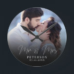 Horloge Ronde Elegant Wedding Photo Chic NewlyWed<br><div class="desc">This elegant script photo clock will be a beautiful keepsake of your wedding day ! Les reads uniques calligraphy reads 'Mr et Mme Alongside your custom family name and date. Add your wedding photo and make this into a perfect vent for the newlywed bride, an anniversary, or vow renewal !...</div>