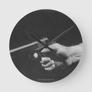 Horloge Ronde Homme tenant un pistolet