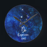 Horloge Ronde Monogramme de ciel de galaxie de constellation de<br><div class="desc">Conception de monogramme de ciel de galaxie de constellation de zodiaque de Capricorne avec la police balayée à la mode de manuscrit, la texture céleste bleu-foncé d'arrière - plan d'aquarelle, la constellation rougeoyante d'étoile, et le symbole de chèvre de mer. L'horoscope astrologique moderne de naissance de signe, est parfait pour...</div>