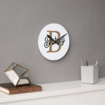 Horloge Ronde Monogramme moderne élégant Nom Black Gold Script<br><div class="desc">L'horloge Monogram Name Black Gold Script Clock est un garde-temps élégant et personnalisé, parfait pour n'importe quelle maison ou bureau. Cette horloge comporte un visage noir élégant avec élégant script or, vous permettant de le customiser avec votre monogramme et votre nom. Le design moderne et les couleurs chics en font...</div>