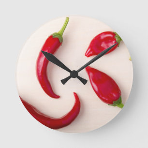 Horloge Ronde Piments rouges chauds sur une planche en bois clai