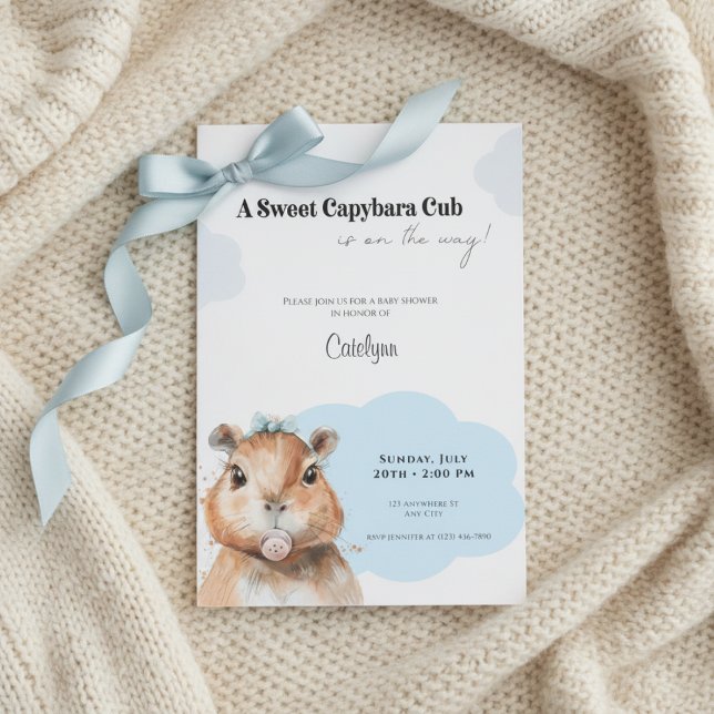 Invitation Fête de naissance Capybara • Thème Ruban Bleu (Baby shower invitation with capybara and blue bow on cream knitted blanket, soft neutral tones.)