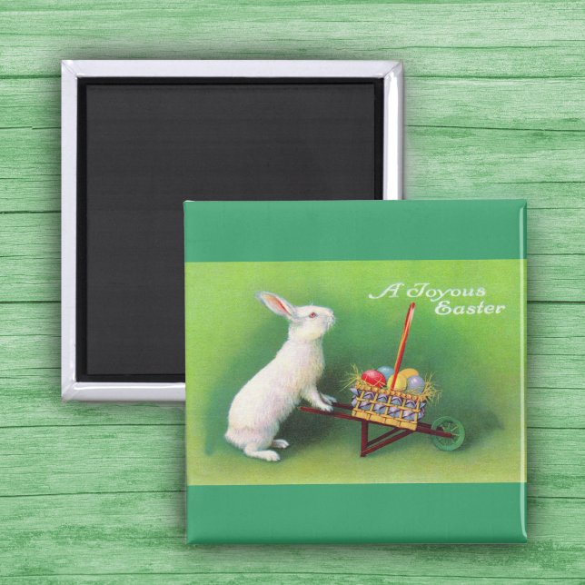 Joyeux lapin de Pâques et aimant à brouette (White Easter Rabbit pushing wheelbarrow with coloured Easter Eggs on green Magnet.)