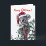 Koala dans une carte de Noël de chapeau de Père No<br><div class="desc">La carte de Noël comporte un koala mignon portant un chapeau de Père Noël et accroché à une branche avec de grandes baies rouges. Customisez le message et le message à l'intérieur de la carte à votre goût.</div>