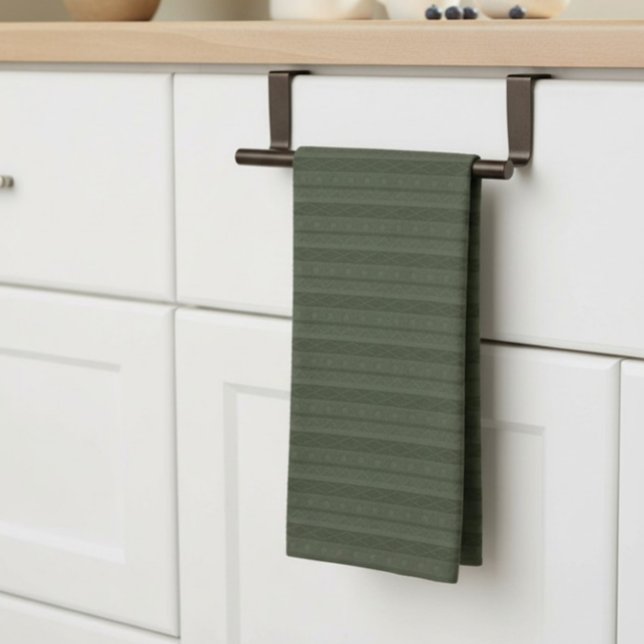 Linge De Cuisine Géométrique Aztec Vert Olive Rayé (geometric, striped, deep green tea towel, neatly hung on a bar on a kitchen counter.)
