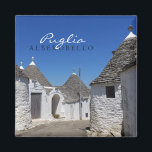 Maisons de Trulli en Alberobello, Pouilles, aimant<br><div class="desc">Aimant photo souvenir avec maisons traditionnelles en plâtre blanc trulli avec tuiles en pierre dans toits coniques dans une petite rue de la ville Alberobello,  Vallée d'Itria dans les Pouilles,  Italie avec le texte : 'Pouilles,  Alberobello'.</div>