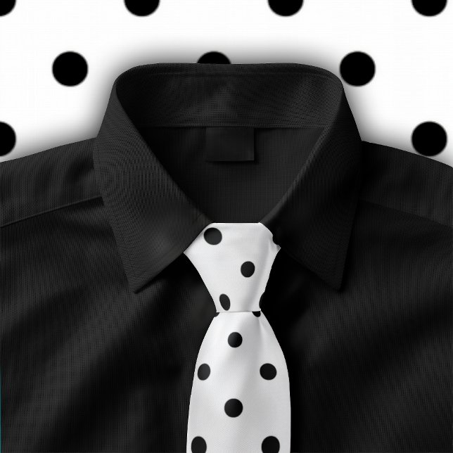 Motif à pois noirs classiques sur une cravate blan (Tie featuring a black polka dot pattern on white is shown on black button down shirt.)
