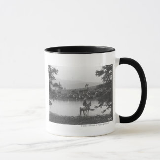 Mug Bétail par un étang avec deux cowboys