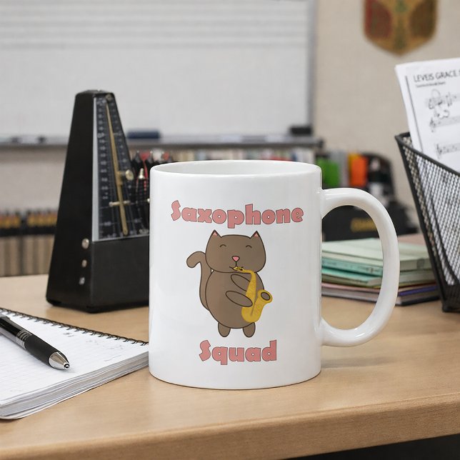 Mug Chat Mignon Jouant du Saxophone “Saxophone Squad”  (A mug with a cute cat playing the saxophone and the words saxophone squad in pink.)