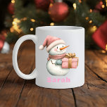 Mug Christmas Snowman Holding Cadeau Nom personnalisé<br><div class="desc">Étalez la joie de vacances avec un Noël Snowman Holding Cadeau Custom Name Mug! Cette délicieuse tasse à café de Noël met en scène un bonhomme de neige dans un casquette rose et une écharpe douillette, avec un cadeau de vacances joliment emballé. Customisez-le facilement avec n'importe quel nom pour créer...</div>