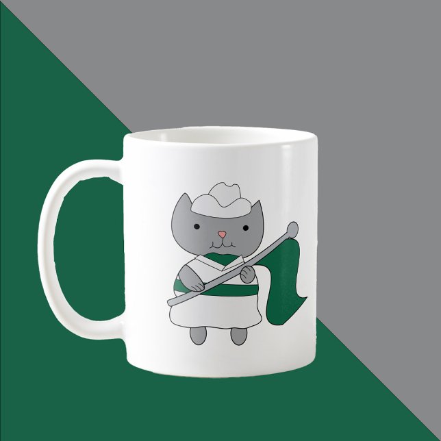 Mug Couleur Garde Chat Vert et Blanc (A mug featuring a gray cat wearing a green and white color guard uniform.)