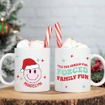 Mug Funny Forced Family Funny Happy Face Personnalisé<br><div class="desc">Ce joyeux Père Noël est le cadeau parfait pour les vacances ! Il est personnalisé avec votre nom et dispose d'un visage rose heureux avec un chapeau de Père Noël et de mignons détails de starburst sur un côté et le texte 'c'est la saison pour le plaisir de famille forcé...</div>