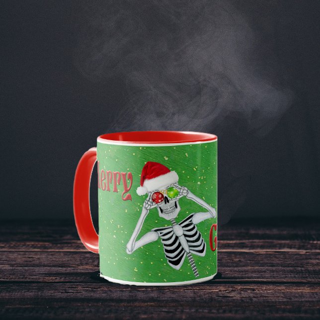 Mug Joyeux Noël Silencieux Squelette Ornement Casquett (Fun Skeleton Ornament eyes Red Merry Christmas text on Green with gold flecks coffee or tea mug.)