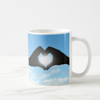 Mug Mains en silhouette de forme de coeur sur le ciel