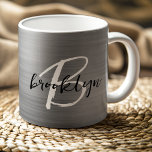 Mug Métal brossé argenté Noir Blanc Script Monogramme<br><div class="desc">Cette élégante tasse à café personnalisée présente un monogramme et un prénom en écriture moderne noir et blanc sur un arrière - plan en métal brossé argent.</div>