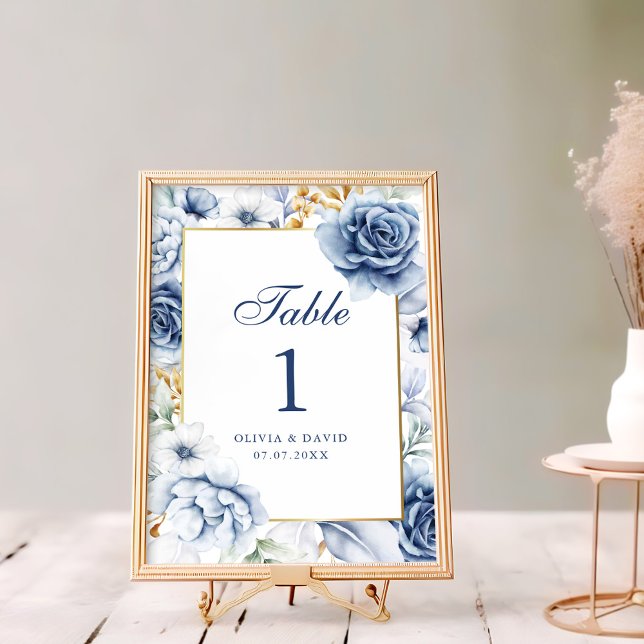 Numéro de table de mariage floral bleu et or moder (Modern Blue and Gold Floral Wedding Table Number on a rustic white wooden table next to flowers)