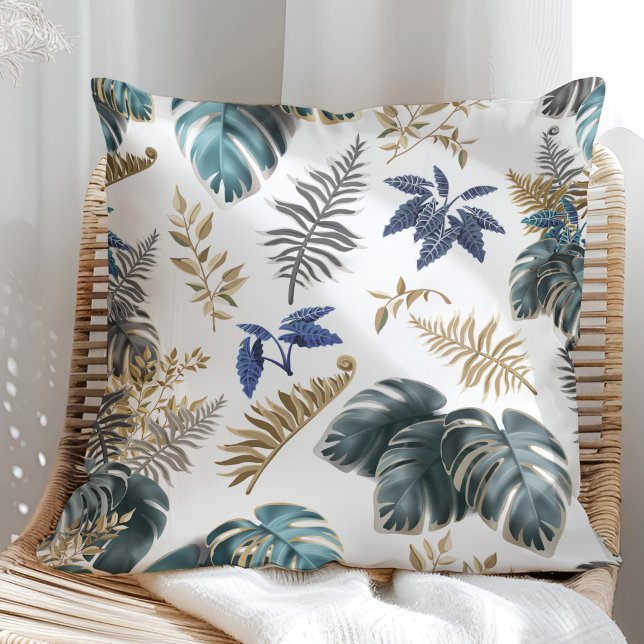 Oreiller à motif de feuilles bleu tropical et doré (Tropical Blue and Golden leaves Pattern Pillow in a sunny rattan armchair.)