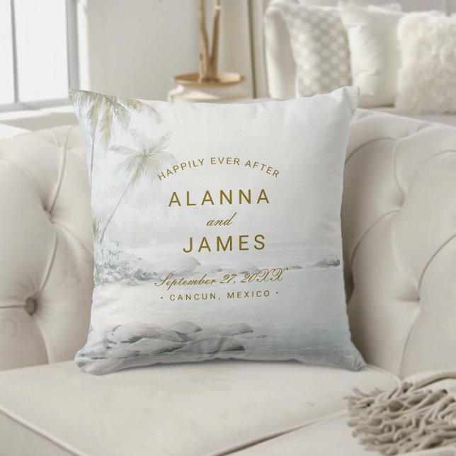 Oreiller de mariage tropical aquarelle sur la plag (Personalized beach wedding pillow with “Alanna and James” text on a cream tufted couch.)
