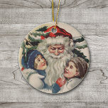 Ornement de Noël du Père Noël vintage<br><div class="desc">Voici une image de Père Noël qui réchauffe le coeur de l'ère victorienne,  embrassant deux petits enfants. Le dos de ce beau ornement est en rouge de Noël,  avec les mots personnalisables "Joyful Christmas 2012". Célébrez Noël à l'ancienne avec cette image d'art vintage.</div>
