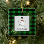 Ornement en céramique plaqué Snowman Green Buffalo<br><div class="desc">Décorez votre arbre cette saison de vacances avec un ornement en céramique de Buffalo Vert Snowman. La décoration ornementale comprend une boîte ornée de branches de pin et un charmant bonhomme de neige contre un arrière - plan de buffle. Autres cadeaux et objets de vacances disponibles avec ce design aussi....</div>