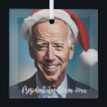 Ornement En Verre Le président Joe Biden et Santa Hat<br><div class="desc">Ce dessin présente une caricature de Joe Biden portant un chapeau de Père Noël sur un arrière - plan bleu.</div>