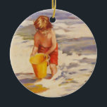 Ornement Rond En Céramique Beach Boy Enfant dans les vagues de l'océan<br><div class="desc">Petit garçon plongeant son seau dans les vagues de l'océan C'est une belle peinture d'un petit garçon qui prend de l'eau de l'océan dans son petit seau jaune. Le jeune garçon a des cheveux bruns, des maillots de bain rouges et un seau jaune vif. Les vagues de l'océan à la...</div>