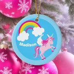 Ornement Rond En Céramique Cute Unicorn Rainbow Custom<br><div class="desc">Un beau cadeau fantaisiste de Noël pour une fille qui aime des cadeaux très personnalisés. Dispose d'une mignonne licorne rose avec des ailes blanches sautant dans l'air à côté d'un bel arc-en-ciel sur l'arrière - plan du ciel. Customisez avec votre nom.</div>