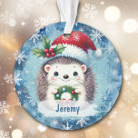 Petit-enfant du Père Noël Hat<br><div class="desc">Voici un joli ornement de Noël pour ce petit-fils ou petite-fille spécial ! Un petit hérisson tient une couronne et porte un casquette du Père Noël rouge et blanc décoré de saints et de baies. L'image est placée sur un arrière - plan bleu avec des flocons de neige blancs. Le...</div>