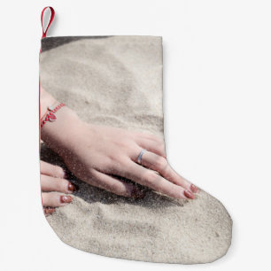 Petite Chaussette De Noël Femme allongée sur le sable blanc