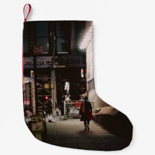 PETITE CHAUSSETTE DE NOËL FEMME EN ROBE NOIRE ET ROUGE MARCHANT LE LONG DE B