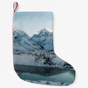 PETITE CHAUSSETTE DE NOËL NEIGE COUVERTE MONTAGNE PRÈS DU CORPS D'EAU