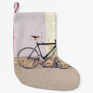 PETITE CHAUSSETTE DE NOËL VÉLO DE VILLE NOIRE ET GRIS S'APPUYANT SUR MUR BLA
