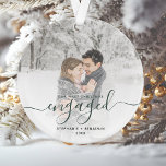 Photo personnalisée Premier Noël Engagé Script ver<br><div class="desc">Commémorez votre fiançailles avec ce magnifique ornement de gardien moderne. Le texte vert de pin foncé dit "Notre premier Noël engagé", avec le mot "engagé" dans un élégant script d'écriture manuscrite avec des fleuris avant et après. Remplacez l'exemple d'image par votre photo préférée, et ajoutez vos noms et l'année. Un...</div>
