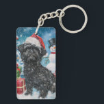 Porte-clefs Affenpinscher Winter Wonderland Christmas Joie<br><div class="desc">Ce design festif reflète l'esprit joyeux de la période des fêtes, avec un adorable petit portant un chapeau de Père Noël. Le chien est niché dans un pays des merveilles hivernales, avec un bonhomme de neige, un sapin de Noël décoré et des cadeaux joliment emballés. Les flocons de neige tombent...</div>