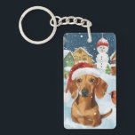 Porte-clefs Dachshund Winter Wonderland Christmas Joy<br><div class="desc">Ce design festif reflète l'esprit joyeux de la période des fêtes, avec un adorable petit portant un chapeau de Père Noël. Le chien est niché dans un pays des merveilles hivernales, avec un bonhomme de neige, un sapin de Noël décoré et des cadeaux joliment emballés. Les flocons de neige tombent...</div>