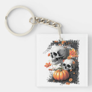 Porte-clefs Deux crânes et un citrouille parmi les fleurs.