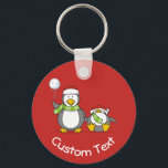 Porte-clés Christmas Snowballing Penguins Keychain<br><div class="desc">A little penguin cartoon with snowball and a fainted one. Both wearing green scarfs and santa hats. Custom background color. Custom text on both sides.</div>